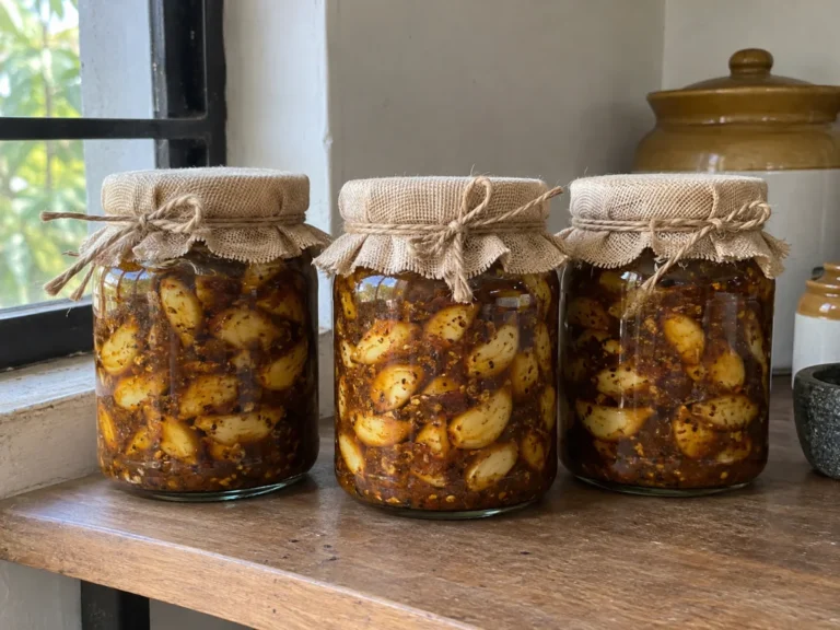 Jars of homemade garlic pickle resting on a kitchen shelf for a week before bottling