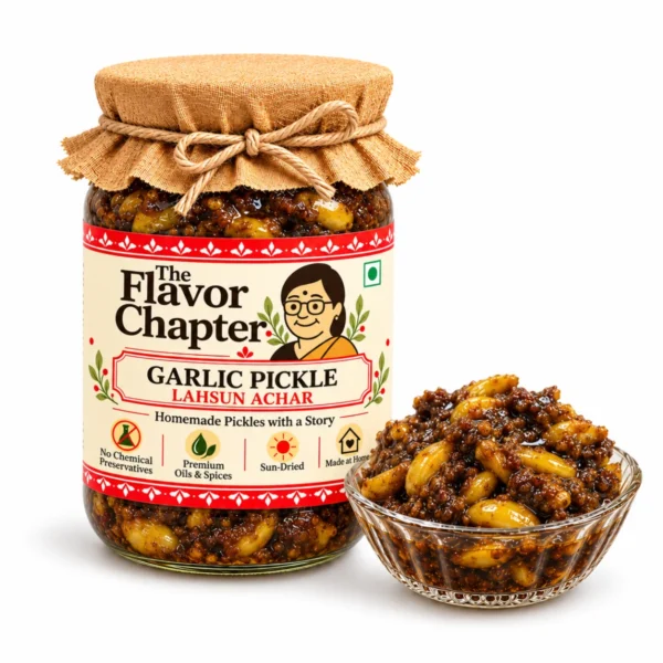 Homemade garlic pickle (lahsun achar) in a The Flavor Chapter jar with a bowl of whole garlic cloves in dark tamarind and jaggery masala, on white