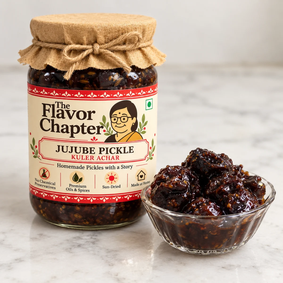 Jar of The Flavor Chapter kuler achar with a glass bowl of dark jujube pickle on a marble counter in a Kolkata home kitchen